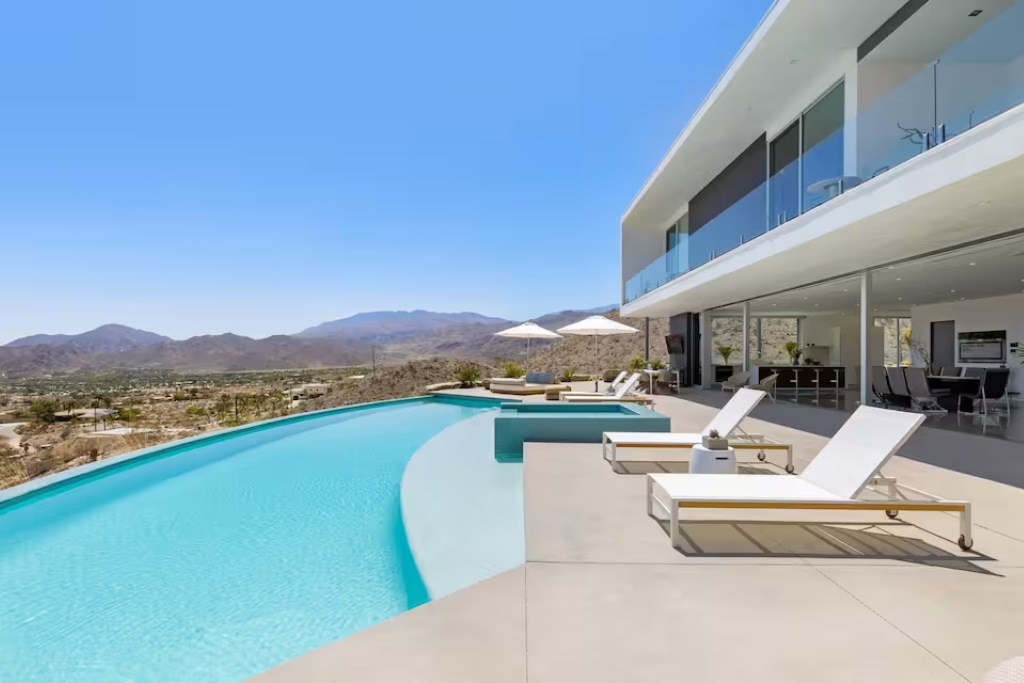 infinity pool looking out over palm desert in a white modern airbnb and lounge chairs