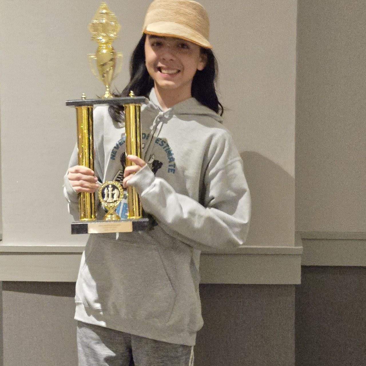 A child holding a trophyDescription automatically generated