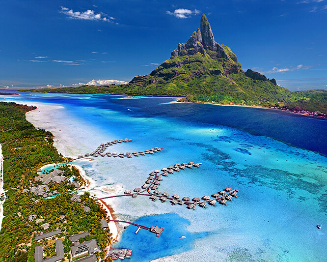 Top view of Bora Bora Island, showcasing its turquoise lagoon, lush greenery, and surrounding coral reefs.