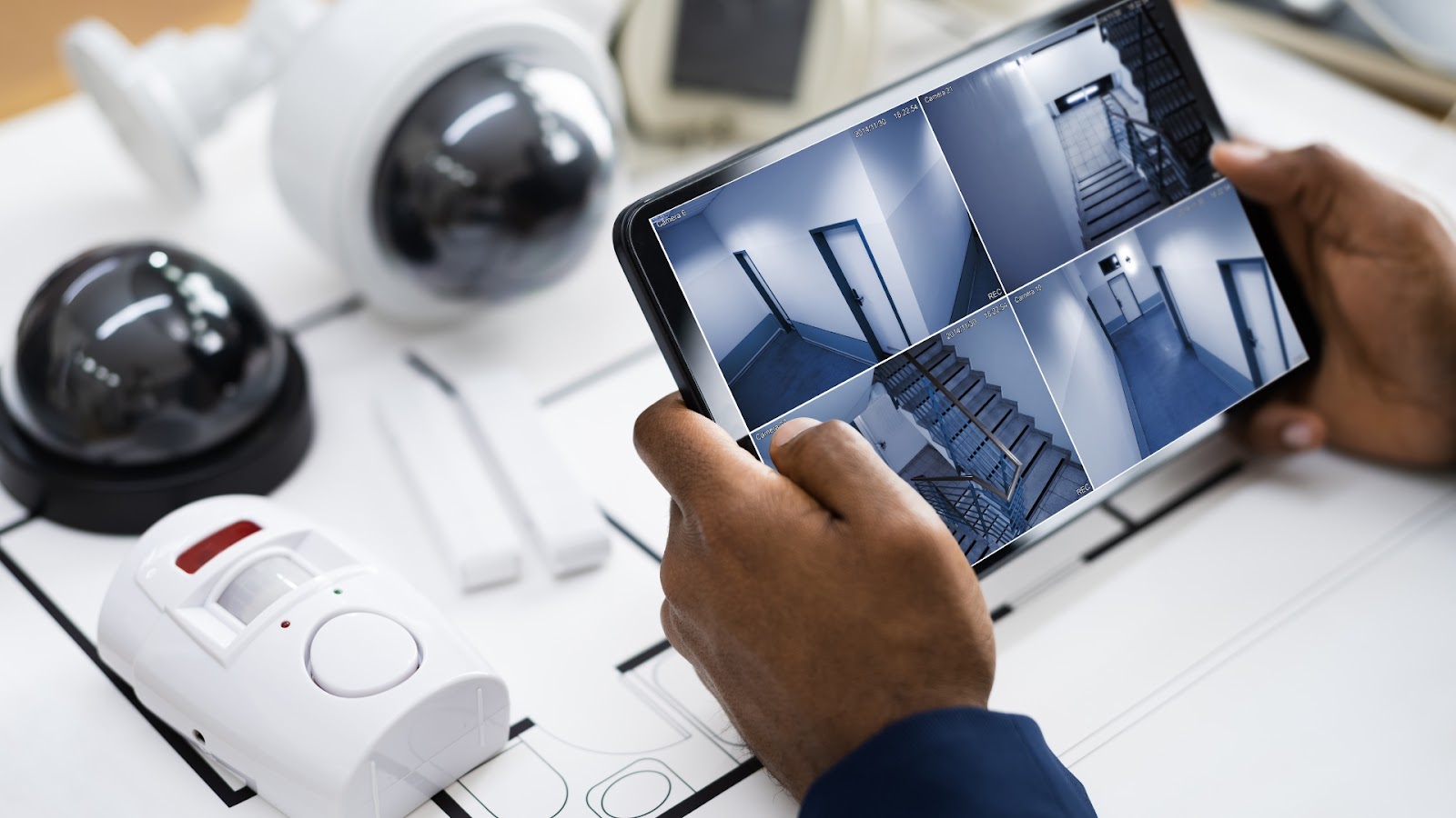 Hands holding a tablet displaying security camera footage.