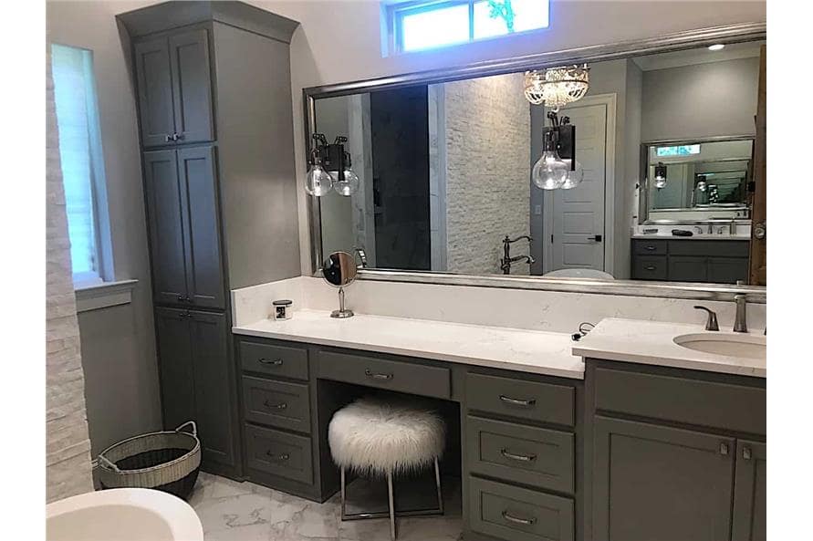 A large vanity equipped with a sink, dark wood cabinets, a large mirror, and a round faux fur stool.