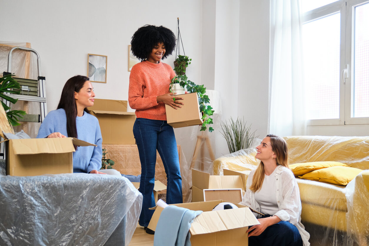 Trois étudiantes souriantes se trouvent au milieu de plusieurs cartons. Elles viennent d'emménager dans un appartement étudiant. Elles se sont demandé quel type de logement choisir selon son budget et ont opté pour la colocation.