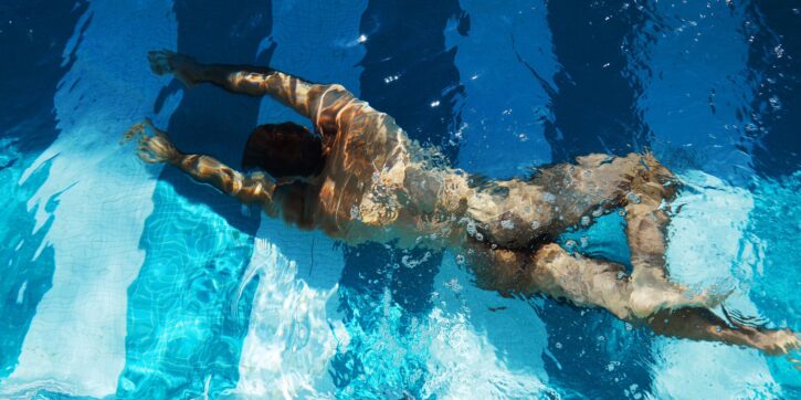 gay porn performer saleh helalat swimming naked in a pool showing off his muscled back