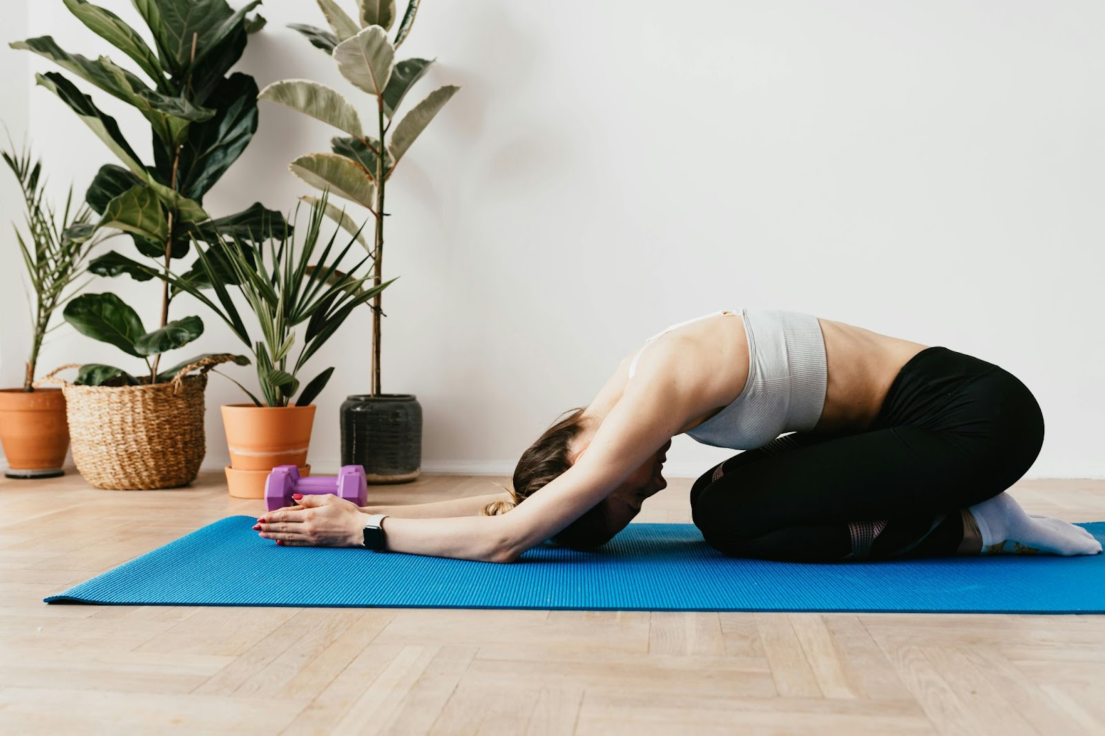 A young white woman in a yoga child's pose on the floor