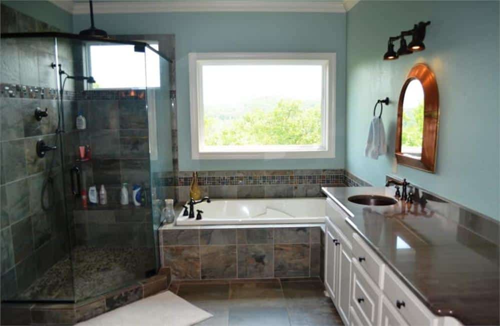 Primary bathroom with a dual sink vanity, a walk-in shower, and a drop-in bathtub brightened by a picture window.