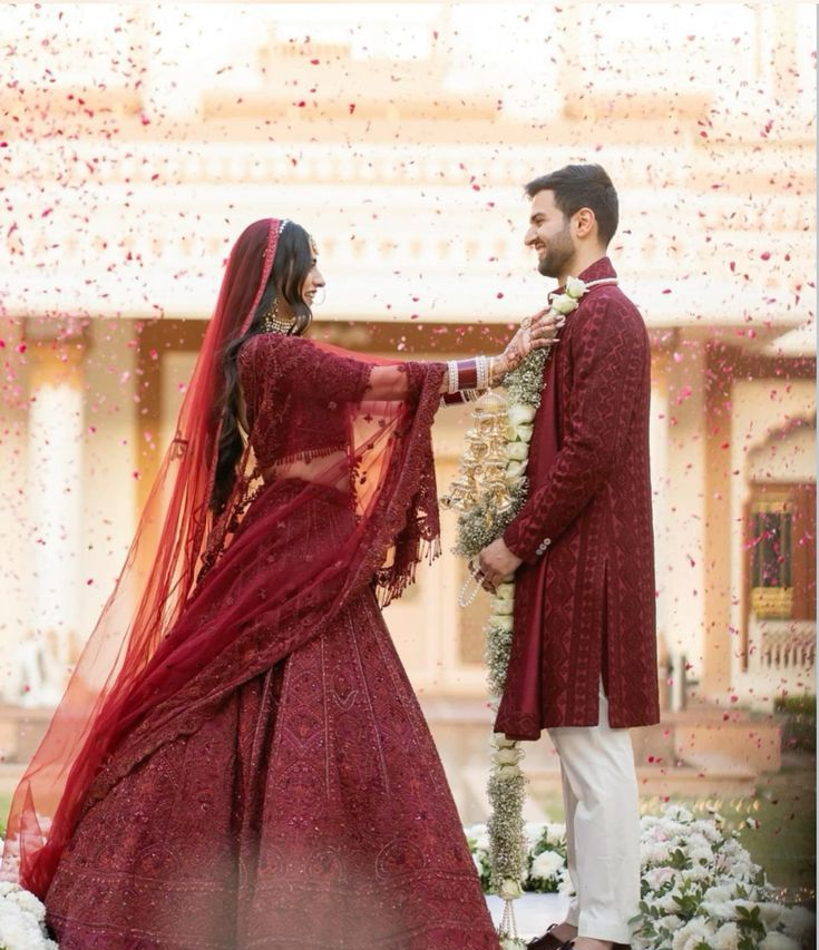 Romantic Varmala ceremony moment with a couple exchanging garlands amidst a shower of rose petals at their wedding.