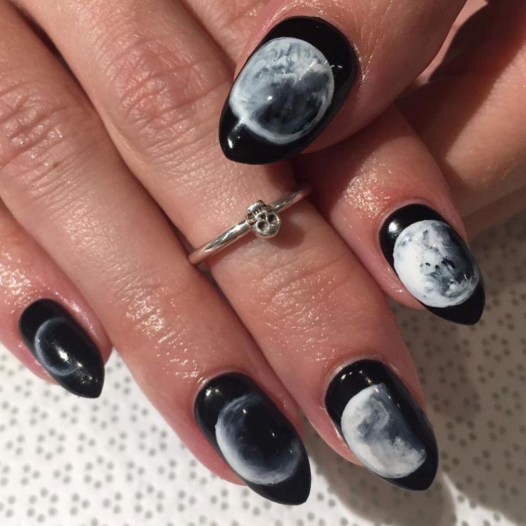 Close-up of a person's hands with black nails having Moon Phase Nail Art