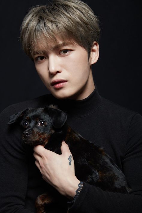 This  contain Kim Jaejoong  holding a small dog in his arms and looking at the camera with an intense look on his face