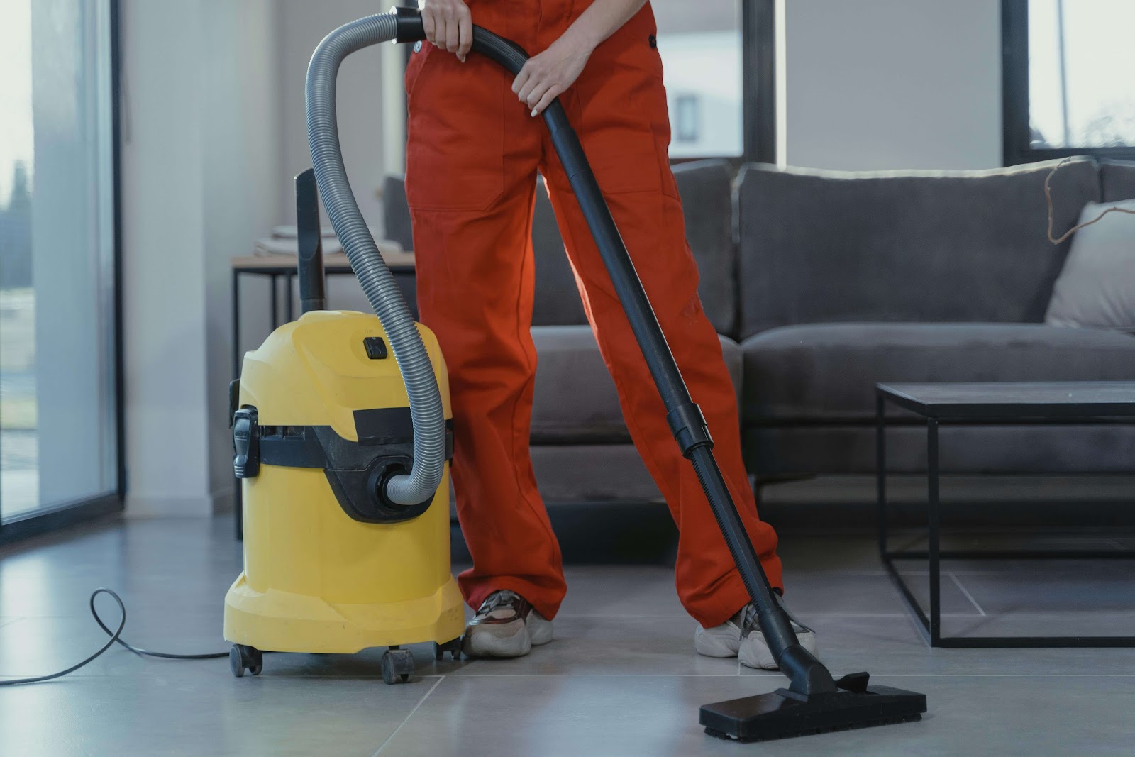 A woman using a large vacuum to clean the floors of a home.