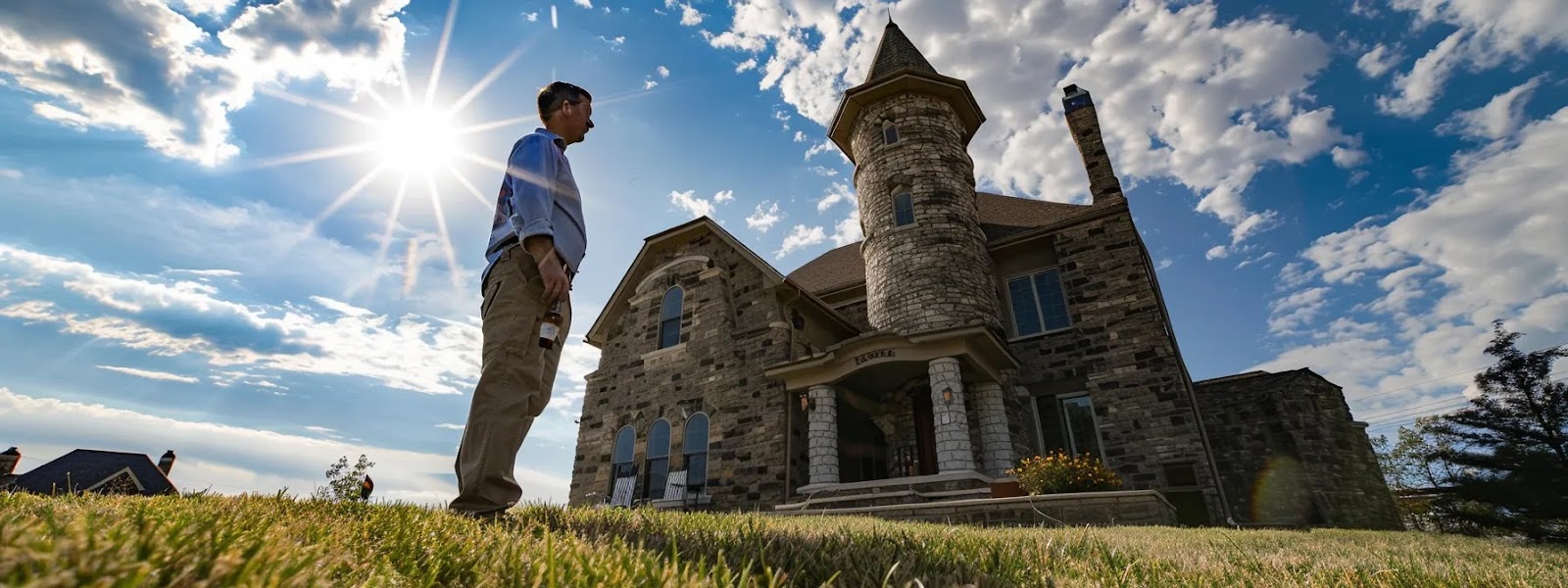 a confident homebuyer stands in front of a sturdy keystone castle, with a clear blue sky overhead, as a professional inspector examines the foundation, symbolizing trust and thoroughness in the pa loan process.