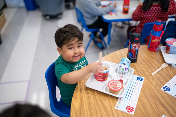 Picture of an elementary age student eating breakfast. 