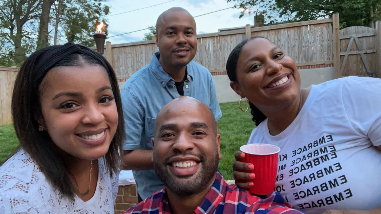 A selfie with two men and two women in a backyard setting.