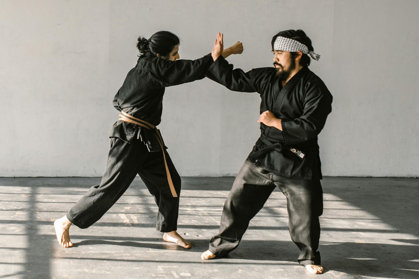 A martial arts instructor training a student how to block