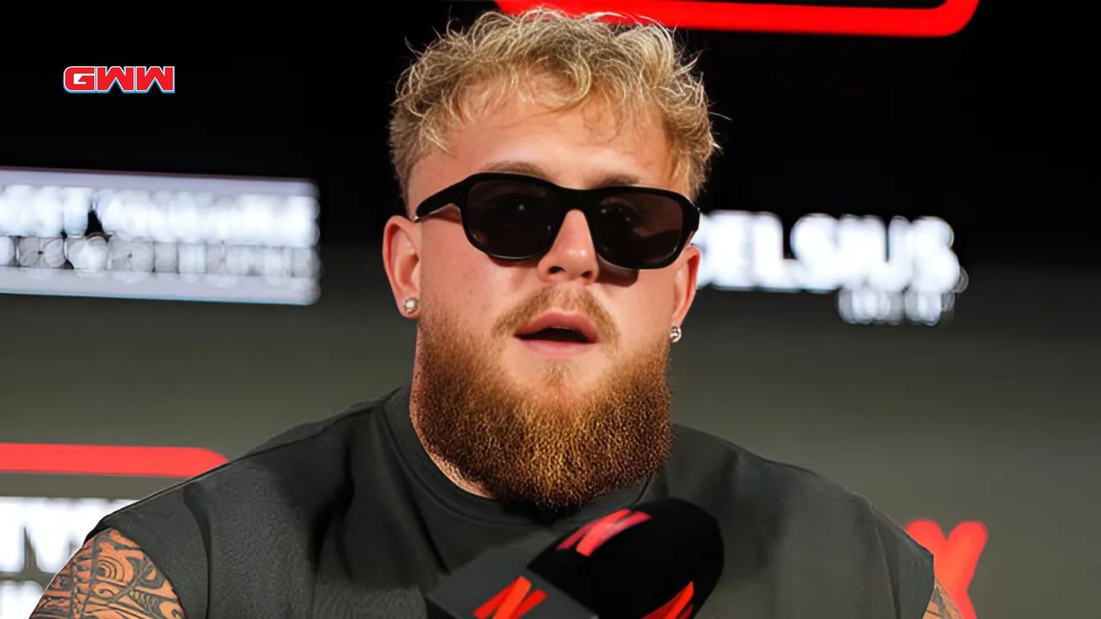 Jake Paul wearing sunglasses speaking at a media event