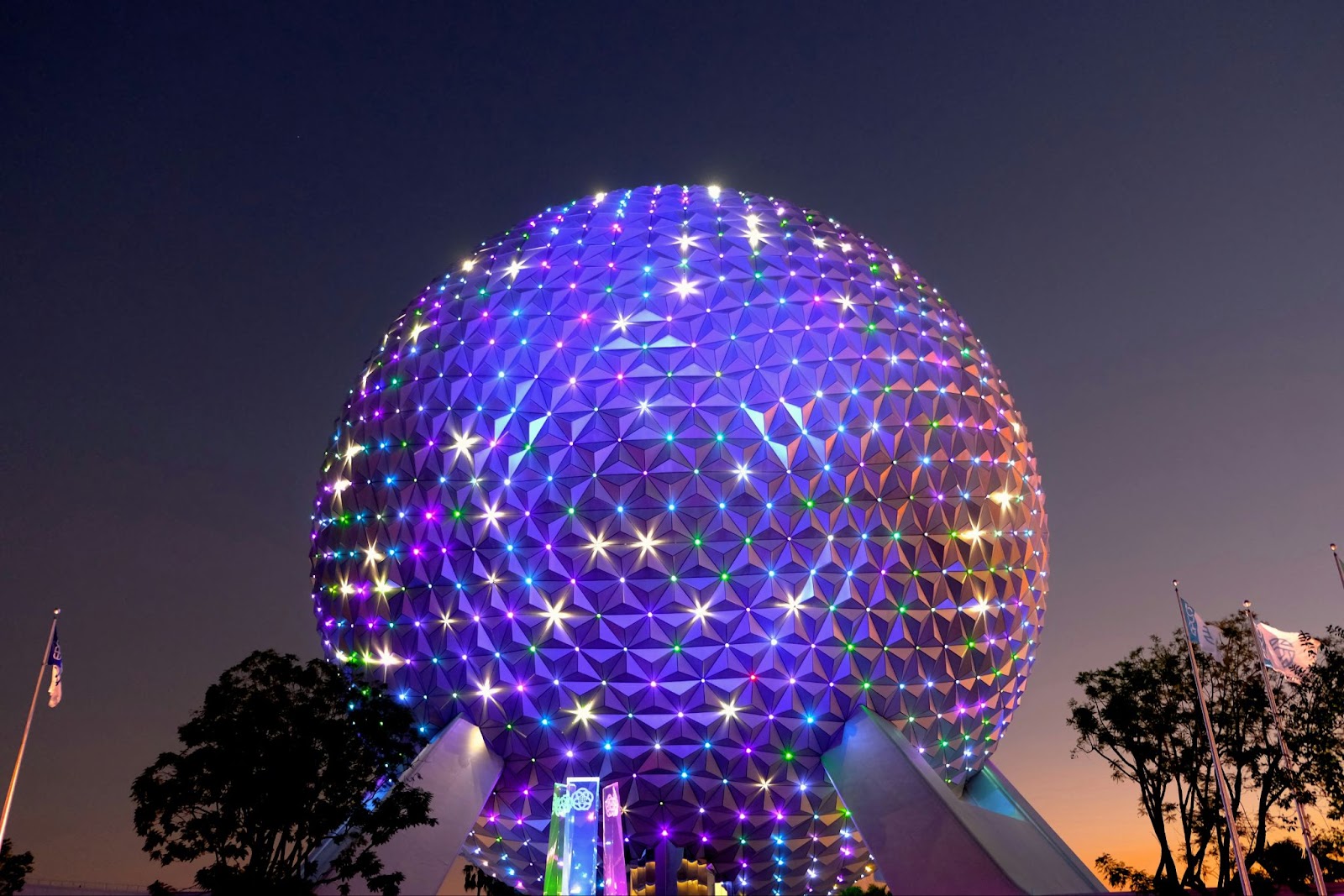 Disney's Epcot sphere glowing in lights at dusk
