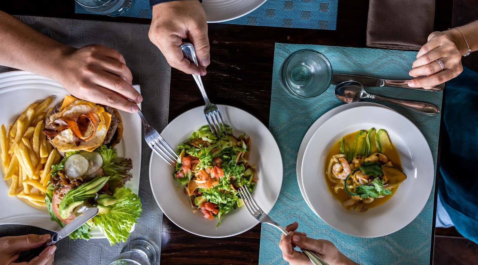 Des convives savourant des repas sains, comme des salades et des fruits de mer, dans une alternative à la restauration rapide, fortement recommandée pour des régimes équilibrés.