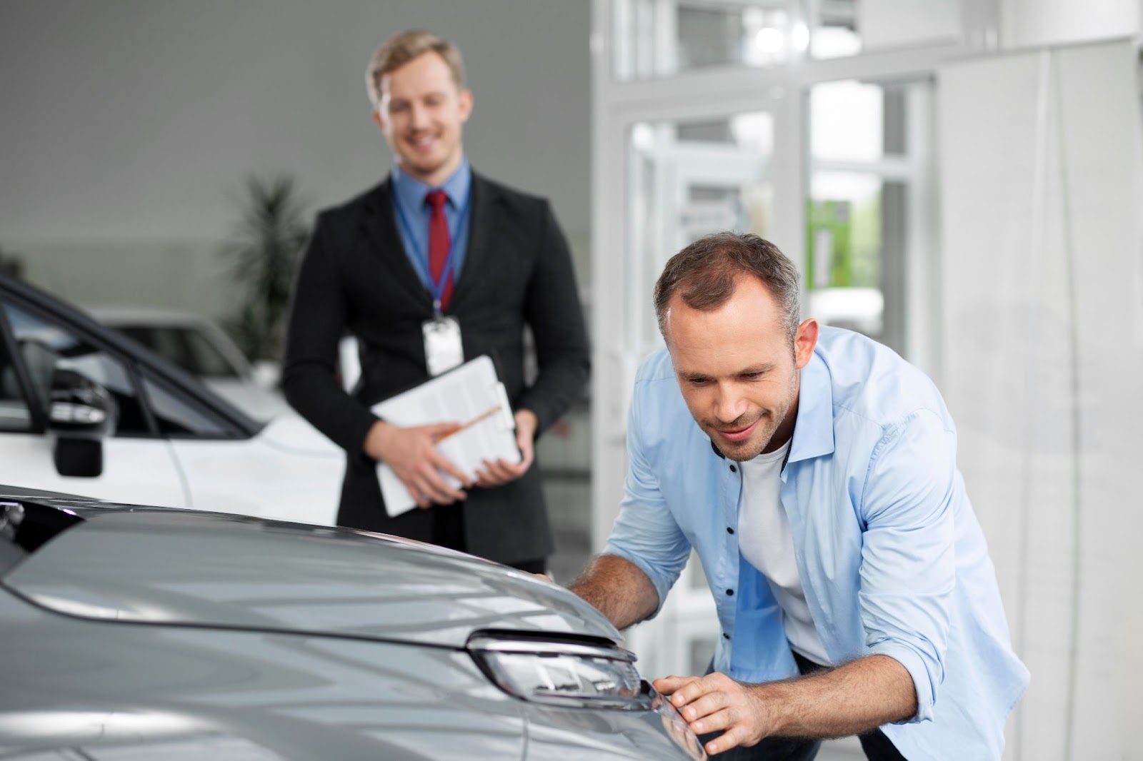 A customer examines a car closely to avoid car dealership fraud