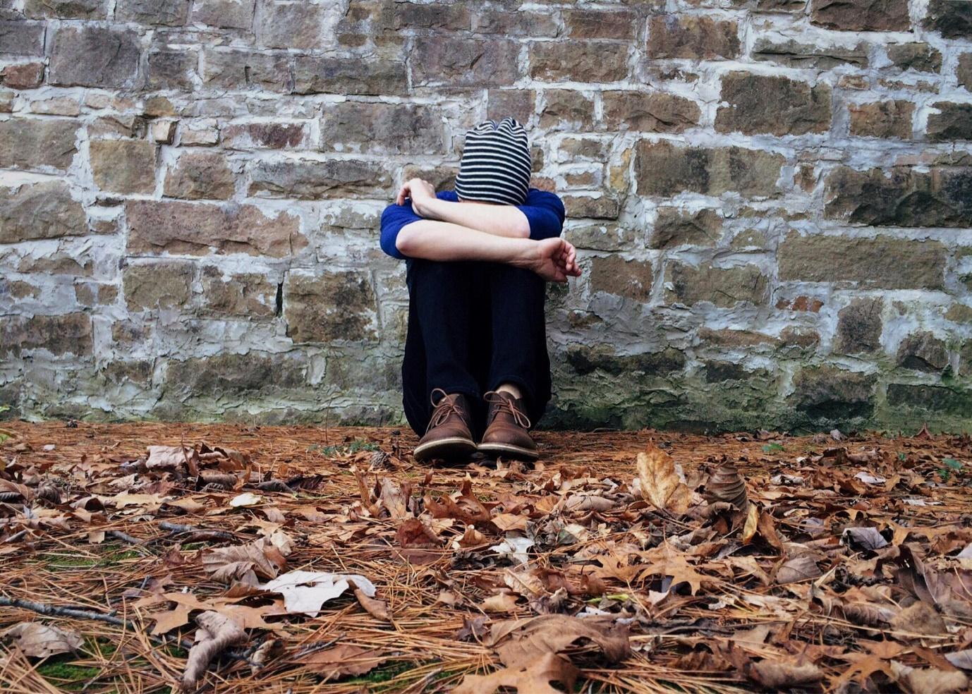 A person sitting in front of a brick wall

Description automatically generated