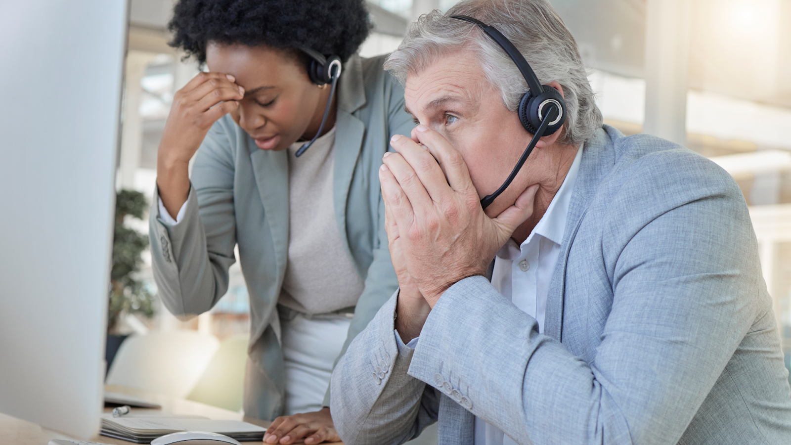 Client support employees grabbing their heads in concern because one client is having tech problems and they do not have a clue how ti fix them