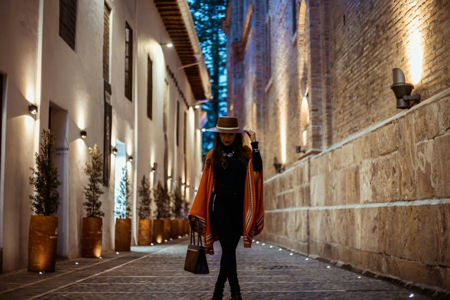 woman in black dress and brown hat walking down the street