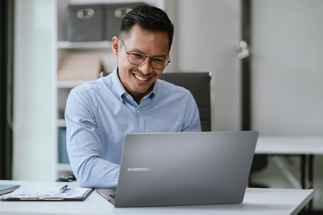  Homem sorridente usando um notebook corporativo no escritório.