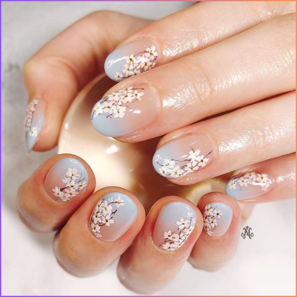 Close up of hands with flowered designed blue nails having Ombre with Cherry Blossom Design