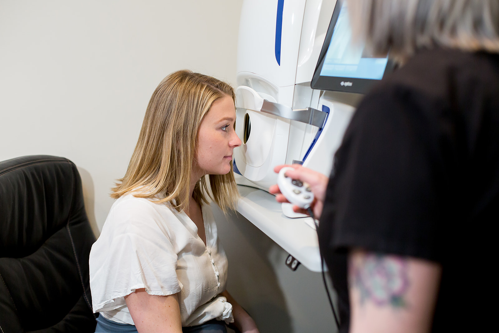 Staff at Tutt Street Optometry taking measurements of a young patient's eye during an eye exam.