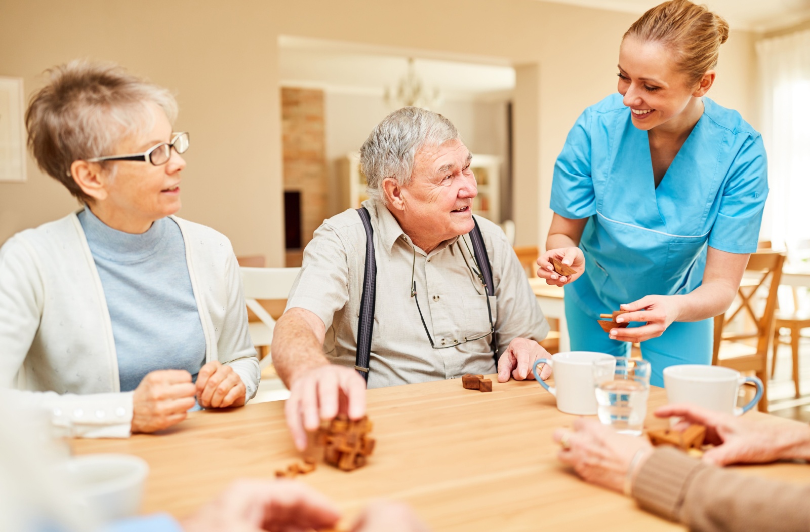 Caregiver assisting seniors with a puzzle activity in an assisted living community.