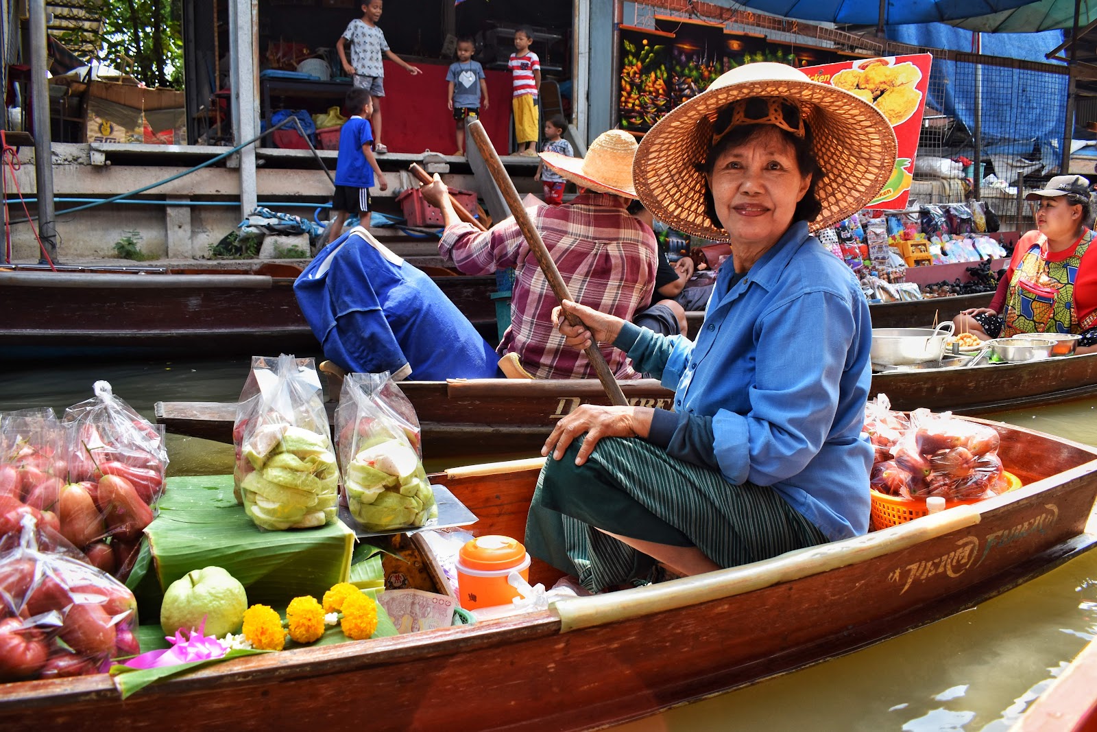 a lady selling fruits and vegetables at a floating market in bangkok