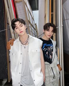 This contains a picture of Vernon and Dino  standing next to each other in front of wooden frames and doors with their hands in their pocket 