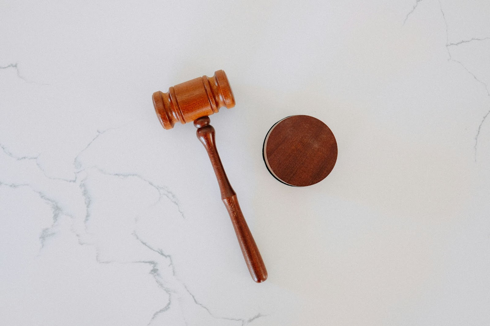 A wooden gavel and sound block on a marble surface, symbolizing justice and law in a minimalistic courtroom setting