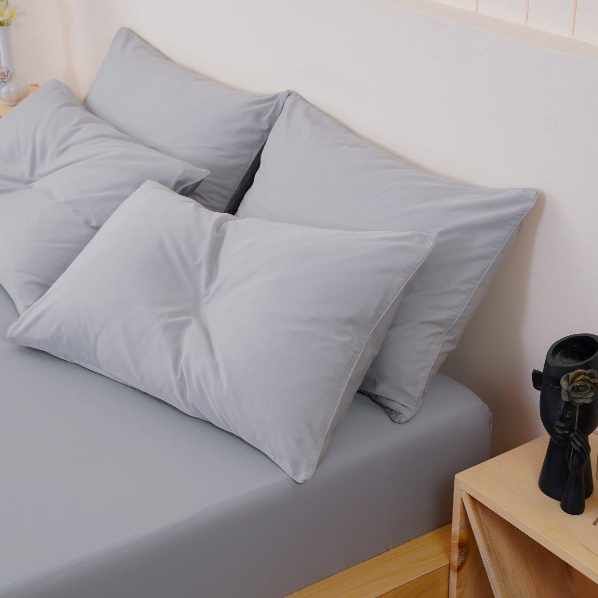 A bed with grey sheets and pillows