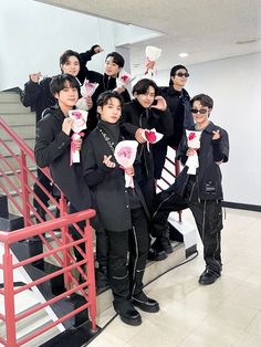 This may contain BTs group on black outfit  standing next to each other on top of a stair case holding flower