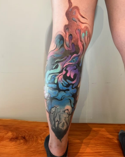 An elaborate tattoo on the calf covering an old tattoo. 