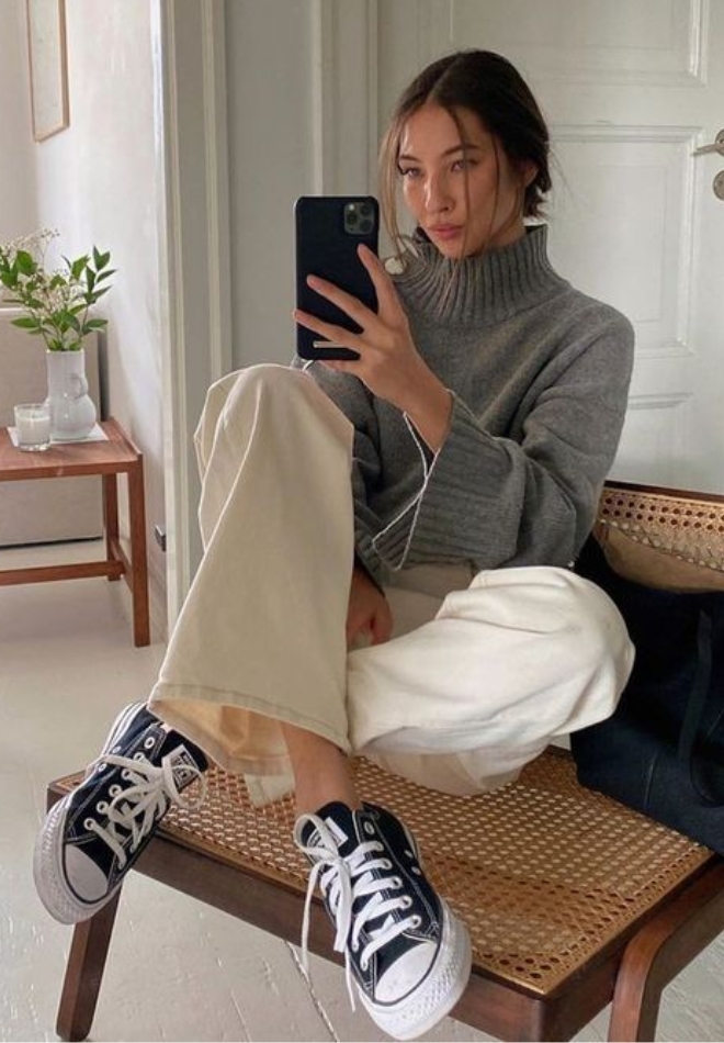 Wanita dengan trouser cream dan turtleneck abu-abu.