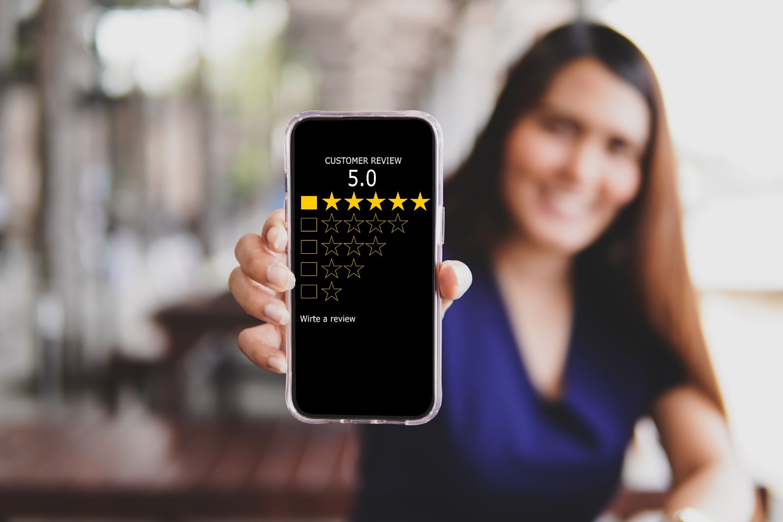 Woman holding a phone with a 5-star review on the screen. 