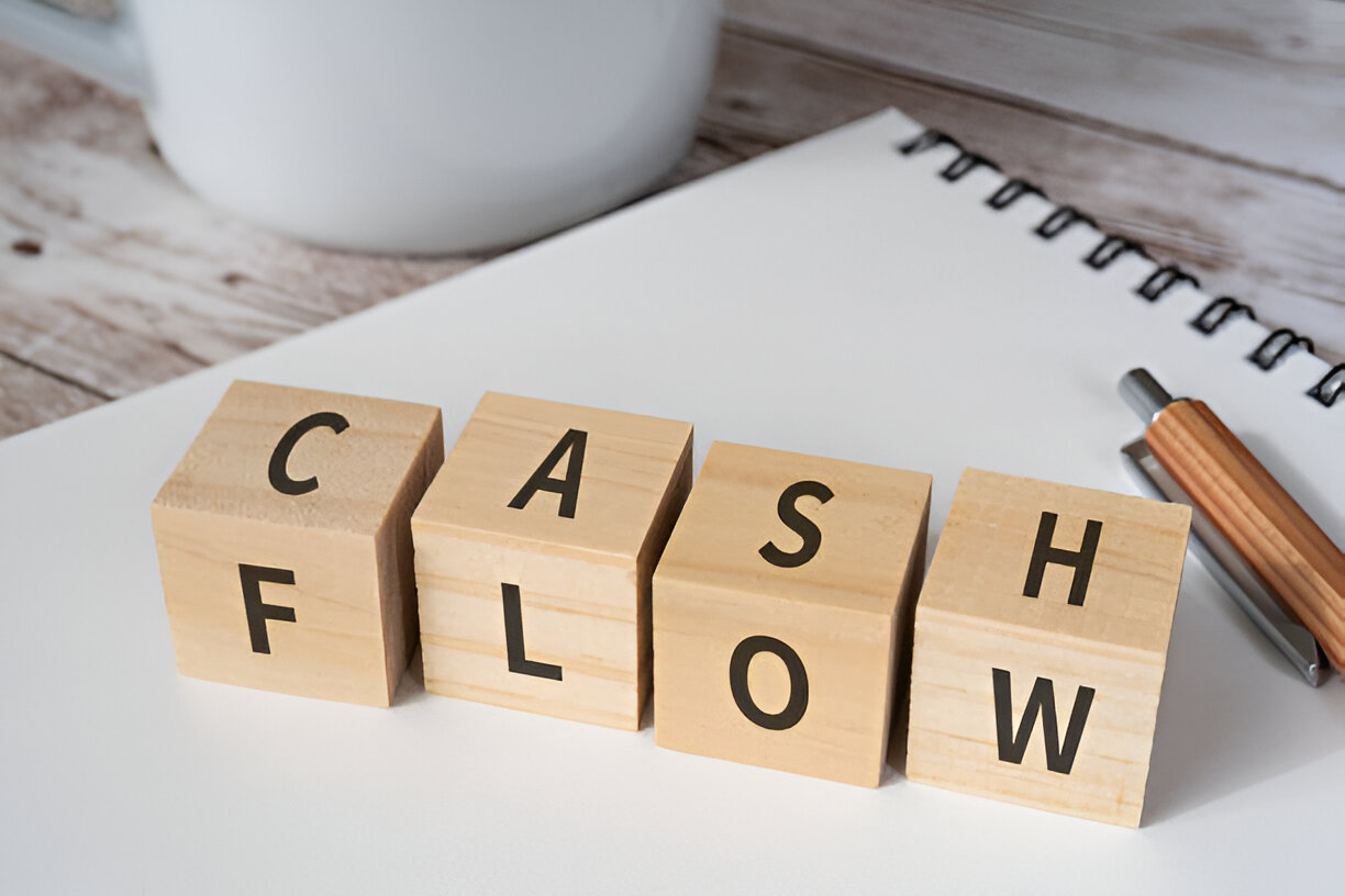 Wooden blocks spelling 'Cash Flow' on a desk, symbolizing the importance of tracking finances for bookkeeping and tax preparation.