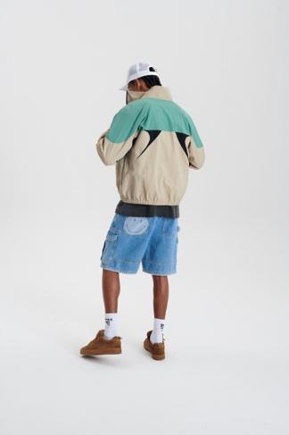 modelo em pe com blusa verde e creme de costas