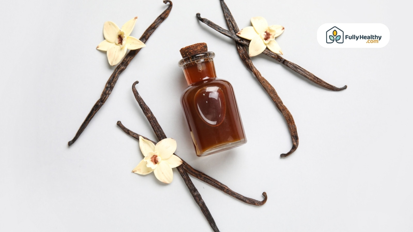 Small bottle of vanilla surrounded by pods and vanilla blossoms