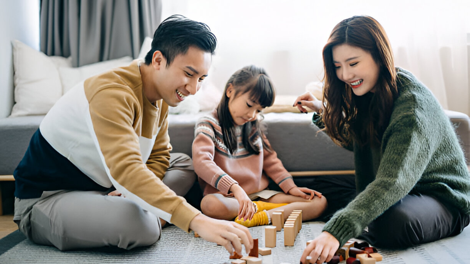 A kid playing with building blocks with her parents.