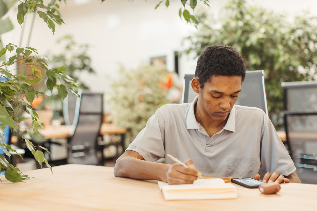 A young man diligently working on his homework at a desk in an office