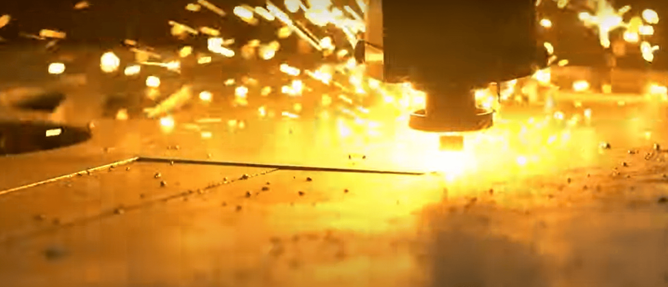 Powerful laser cutter creating precise metal designs with bright sparks during industrial cutting.