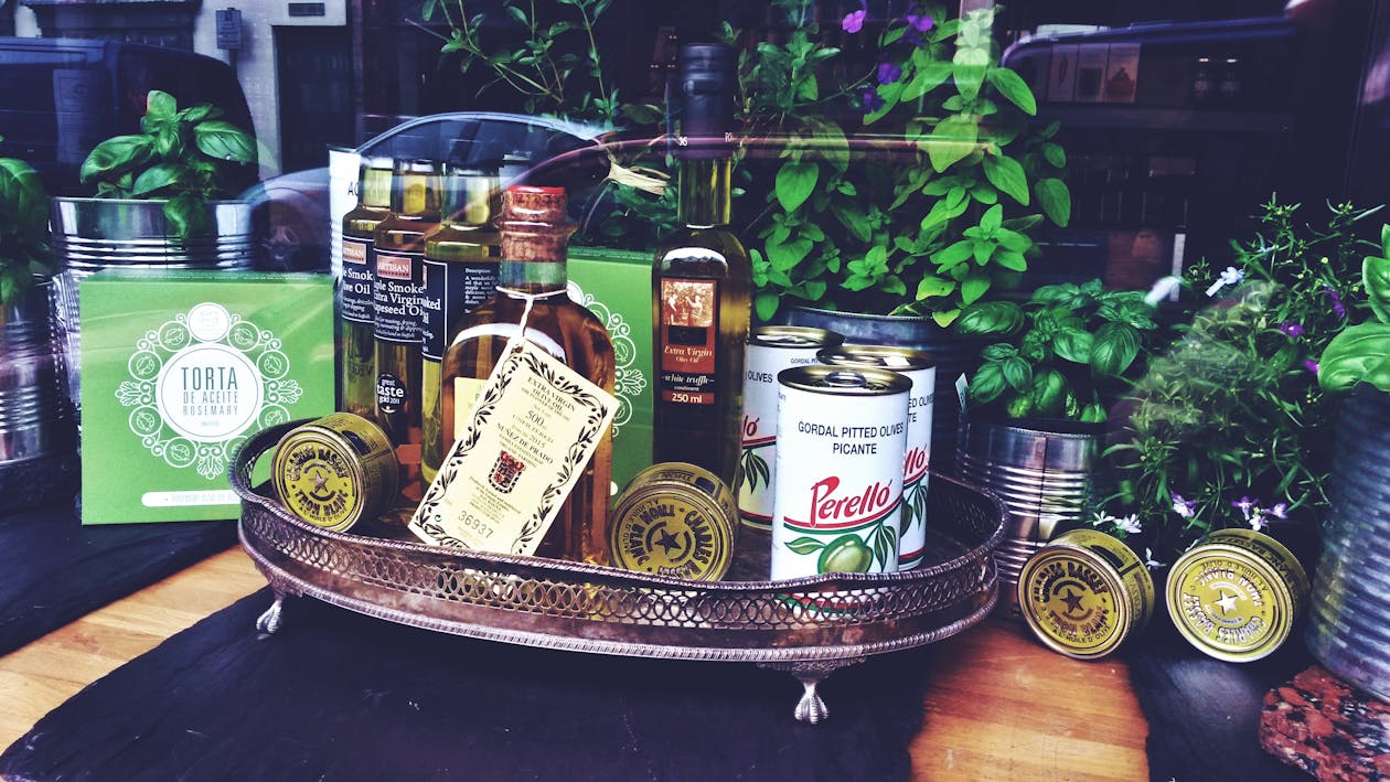 Free Exquisite selection of olive oils, canned olives, and herbs displayed in a cozy shop window. Stock Photo