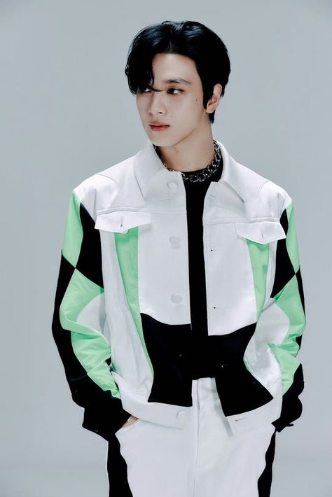 A picture of haechan on a white ouyfit with a touch of green and black with his hands in his pocket 