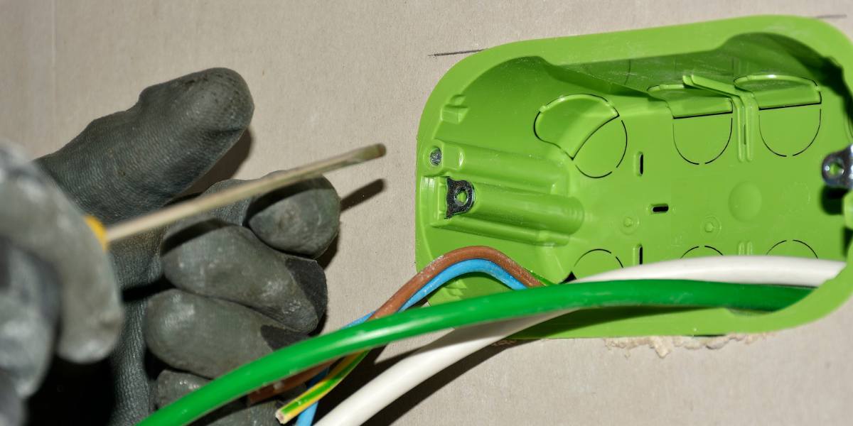 Close-up of a Journeyman Electrician wiring a green electrical box, showcasing the precision required in residential installations.