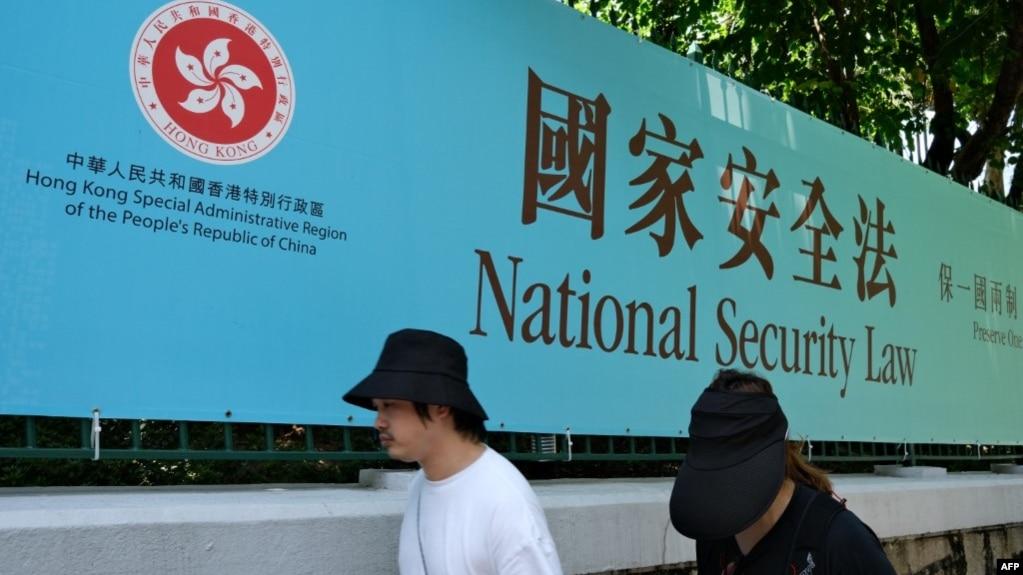 资料照：行人走过香港街头港版国安法的宣传牌。（2020年7月15日）