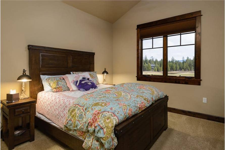 Another bedroom with a vaulted ceiling, carpet flooring, and a wooden framed window that invites natural light in.