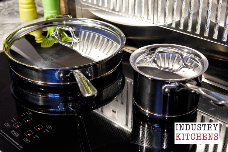 A modern kitchen featuring induction cooktops with various pots and pans arranged on the stove, showcasing cookware compatibility.