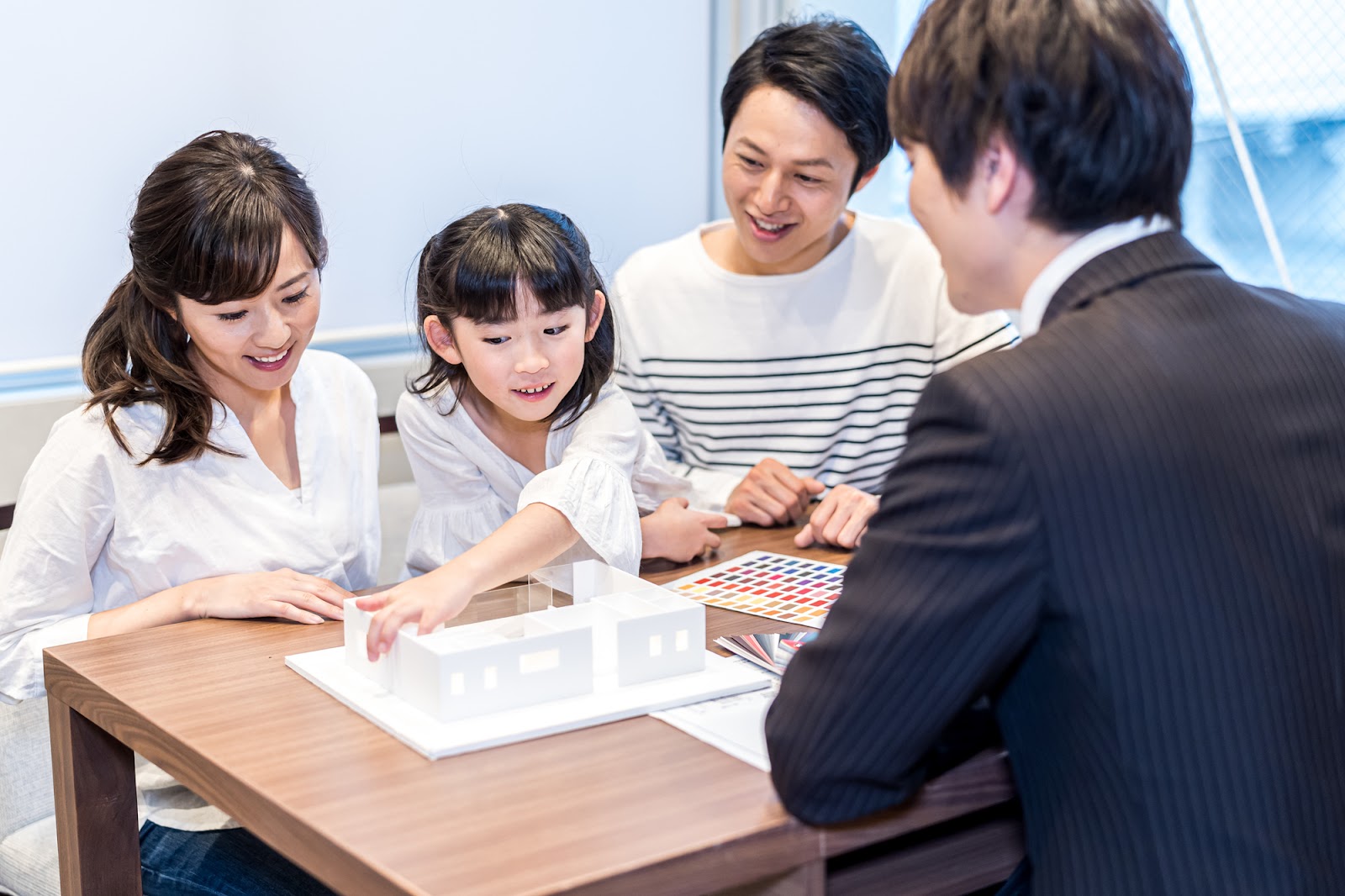 住宅の模型を使って家づくりの打ち合わせをする家族