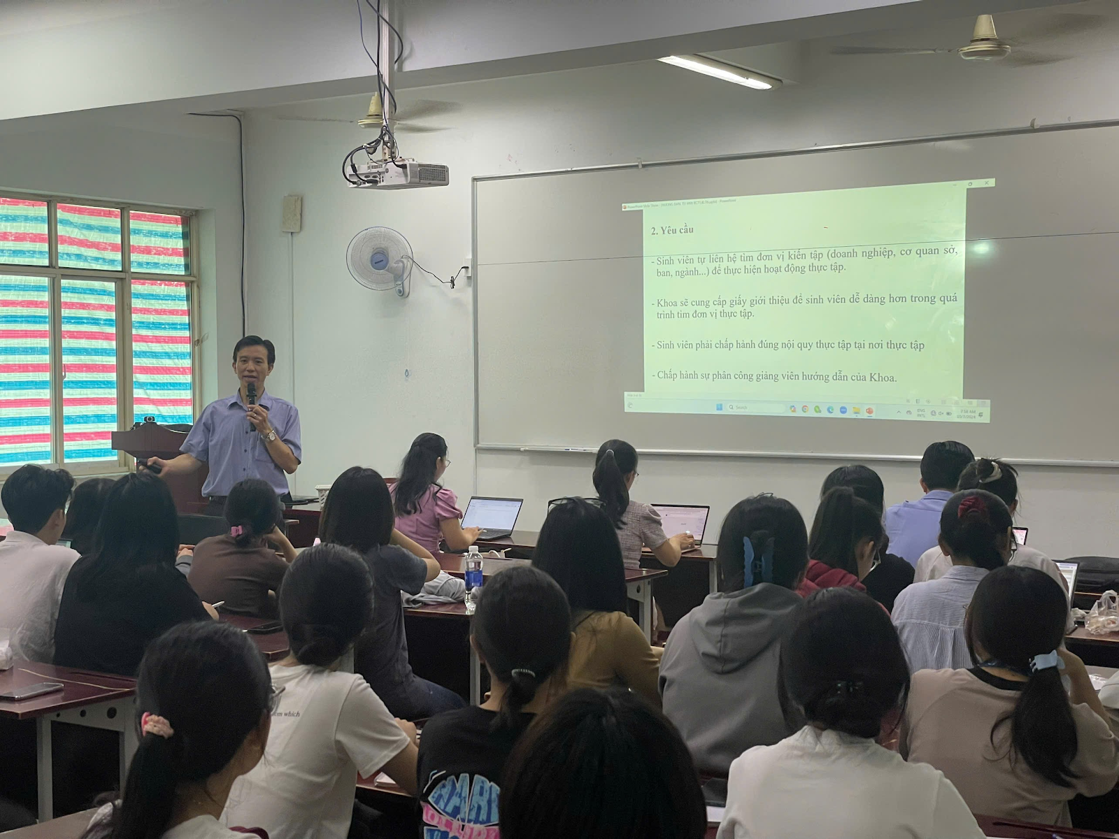 A person standing in front of a classroom with a projector screen
Description automatically generated